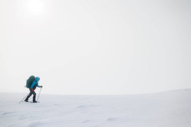 Dağlara tırmanan. Sırt çantalı ve kar ayakkabılı bir kız karda yürüyor. Dağlarda kış yürüyüşü.
