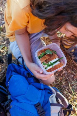 Çocuğun elinde bir beslenme çantası var. Çocuk bir beslenme çantası alır ve yürüyüşe çıkmaya hazırlanır. Sokaktaki yemek. Bir çocukla yürüyüş. seyahat ve macera.