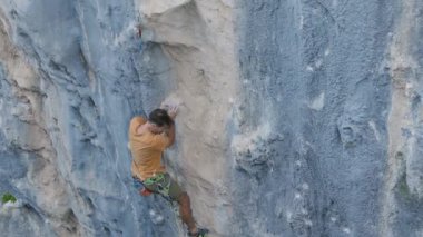 Kaya tırmanışçısı bir kayaya tırmanır. Güçlü bir adam kayaya tırmanır. Güçlü kaslar. Dayanıklılık ve dayanıklılık eğitimi, ekstrem sporlar yapan adam, dağcılık eğitimi.