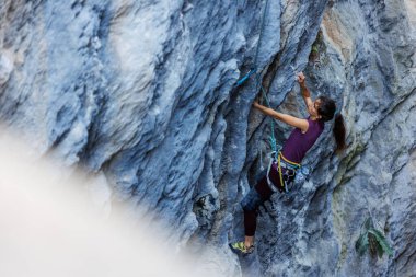 Dağcı kız. Kaya tırmanışçısı bir kayaya tırmanır. Tırmanışçı dağın tepesine tırmanır. Kızlar spor için doğaya giderler..