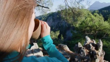 Aktif genç kız bir fincan sıcak çayın tadını çıkarıyor ve yürüyüşe ara veriyor..