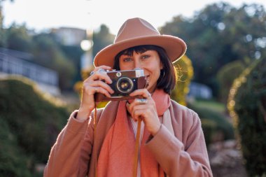 Kameralı genç bir kadın. Kameralı hippi turist kadın. Kız film kamerasıyla fotoğraf çekiyor. Yaşam tarzı konsepti. Film kamerası. Şık görünüş.