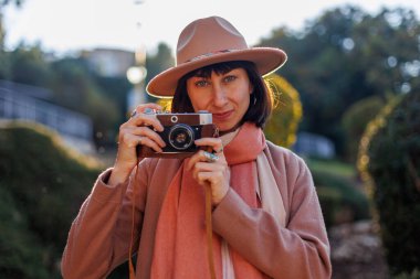 Kameralı genç bir kadın. Kameralı hippi turist kadın. Kız film kamerasıyla fotoğraf çekiyor. Yaşam tarzı konsepti. Film kamerası. Şık görünüş.