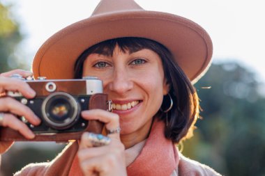 Kameralı genç bir kadın. Kameralı hippi turist kadın. Kız film kamerasıyla fotoğraf çekiyor. Yaşam tarzı konsepti. Film kamerası. Şık görünüş.
