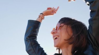 Rock konserinde dans eden ve müzik seven bir kız deri ceketli şık bir kız açık havada dans eden, rock müzik yapan, güneş gözlüklü mutlu bir kadın..