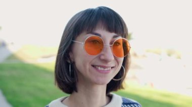 Kaldırımdaki kız. Güneş gözlüklü genç ve şık bir kadın sokakta yürüyor. siyah deri ceket ve kazak. moda ve tarz.