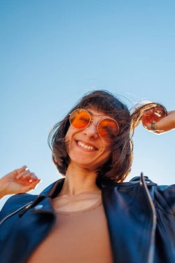 Rock konserinde dans eden ve müzik seven bir kız deri ceketli şık bir kız açık havada dans eden, rock müzik yapan, güneş gözlüklü mutlu bir kadın..