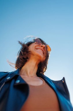 Rock konserinde dans eden bir kız, deri ceketli şık bir kız açık havada dans eden, rock müzik çalan, güneş gözlüklü mutlu bir kadın..