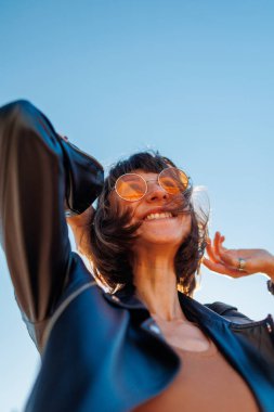 Rock konserinde dans eden ve müzik seven bir kız deri ceketli şık bir kız açık havada dans eden, rock müzik yapan, güneş gözlüklü mutlu bir kadın..