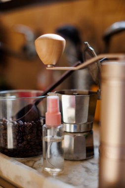 Evdeki masada Moka pot var. Kahve yapma konsepti. Moka demliği, fasulye spreyi, kahve öğütücü, mutfak masasının üzerinde duran bir kavanoz kahve çekirdeği. Kahve yapmak için gerekli malzemeler.
