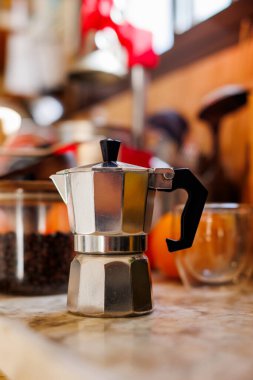 Kahve yapmak için gerekli malzemeler. Moka demliği, fasulye spreyi, kahve değirmeni ve kahve çekirdekleri mutfak masasında duruyor. Kahve yapma konsepti.