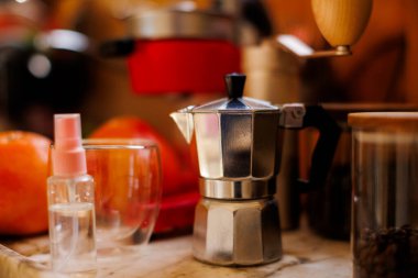 Kahve yapmak için gerekli malzemeler. Moka demliği, fasulye spreyi, kahve değirmeni ve kahve çekirdekleri mutfak masasında duruyor. Kahve yapma konsepti.