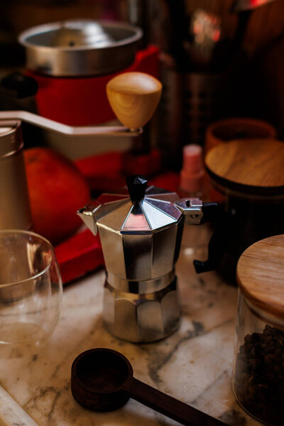 Moka pot on the table at home. Coffee making concept.  Moka pot, bean spray, coffee grinder, jar of coffee beans standing on the kitchen table. Ingredients for making coffee.
