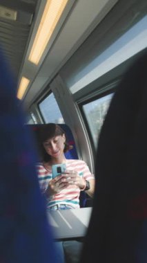 Dikey çekim. Tren yolculuğu. tren yolcusu. Toplu taşıma. Trendeki kadın. Trenle seyahat ederken akıllı telefonlu genç bir kadın. Seyahat kavramının tadını çıkarıyorum. Şık ve şık..