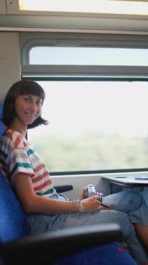 Dikey çekim. Tren yolculuğu. tren yolcusu. Kameralı genç ve güzel bir kız tren yolculuğunun tadını çıkarıyor. İyi yolculuklar..