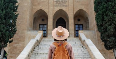 Şapka takan mutlu genç kız binanın güzel manzarasının tadını çıkarıyor. Sırt çantalı kız.