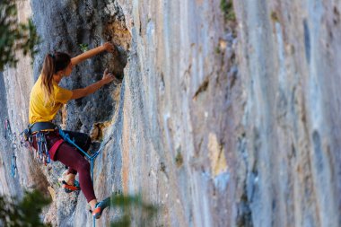  Kız kayaya tırmanıyor. Dağcı kız. Bir olimpiyat sporu olarak kaya tırmanışı. Bir kadın doğada spor yapar.