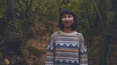 Sırt çantalı kız. Turistin yüzünü yakından çek. Macera ve yürüyüş. Genç mutlu bayan turist ormanda yürüyüş yaparken doğada dinleniyor..