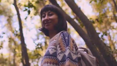 Sırt çantalı, doğa yürüyüşü yapan gülümseyen bir kadın. Güzel bir bayan yürüyüşçü bir dağ yolunda duruyor ve kameraya bakıp gülümsüyor. Yaşam tarzı, macera, aktif yaşam.