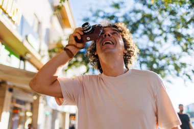 Şehir caddesinde fotoğraf çeken bir fotoğrafçı. Şehir yürüyüşü sırasında kamerayla gülümseyen genç bir turist. Kameralı adam..