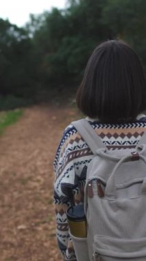 Dikey çekim. Süslü ve sırt çantalı bir kadın seyahat ediyor. Dağlarda yürüyüş. Macera ve yürüyüş. Genç mutlu turist kadın doğada dinleniyor. moda ve tarz.