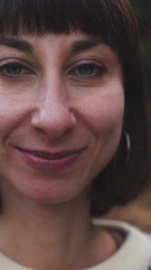 Dikey çekim. Süslü bir kazak giyen ve sırt çantalı bir kız ormanda yürümekten zevk alıyor. Yüzünüzü kapatın. Ormanda yürüyüş. Sırt çantalı bir kız ormanda yürüyor. Yürüyüş ve yürüyüş. moda ve tarz.