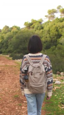 Dikey çekim. Süslü ve sırt çantalı bir kadın seyahat ediyor. Dağlarda yürüyüş. Macera ve yürüyüş. Genç mutlu turist kadın doğada dinleniyor. moda ve tarz.