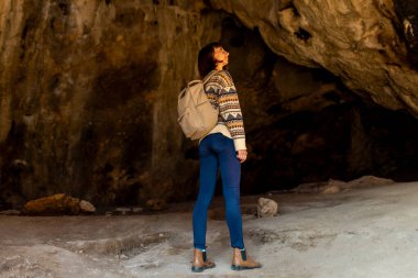 Sırt çantalı genç bir gezgin mağaraları keşfediyor. Mağaraya bir gezi. Kız sırt çantasıyla seyahat ediyor. seyahat ve yürüyüş.