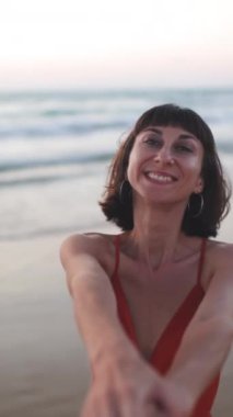 Dikey çekim. Sevgililer Günü. Sahilde elbiseli bir kız. Kumsalda erkek arkadaşıyla yürüyen mutlu genç bir kadın..