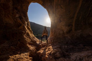 Sırt çantalı kız. Sırt çantalı bir kadın mağarada duruyor. Kız mağarayı keşfediyor. Speleolog. Mağara turu.