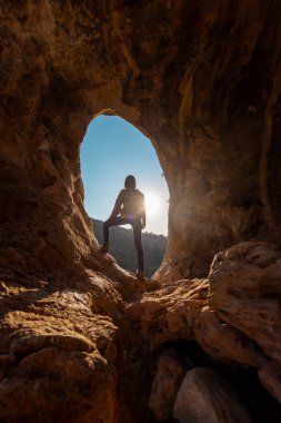 Sırt çantalı genç bir gezgin mağaraları keşfediyor. Mağaraya bir gezi. Kız sırt çantasıyla seyahat ediyor. seyahat ve yürüyüş.