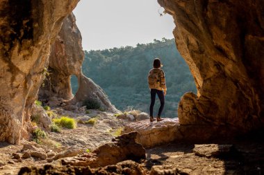 Sırt çantalı genç bir gezgin mağaraları keşfediyor. Mağaraya bir gezi. Kız sırt çantasıyla seyahat ediyor. seyahat ve yürüyüş.