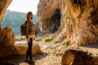 Sırt çantalı genç bir gezgin mağaraları keşfediyor. Mağaraya bir gezi. Kız sırt çantasıyla seyahat ediyor. seyahat ve yürüyüş.