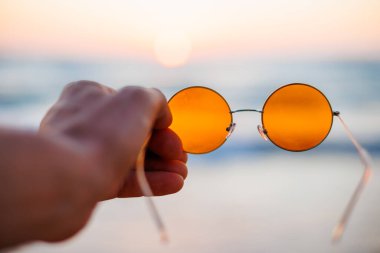 Kız elinde güneş gözlüğü tutuyor. Genç bir kız deniz kenarında tatilin tadını çıkarıyor. Deniz kenarındaki kız.