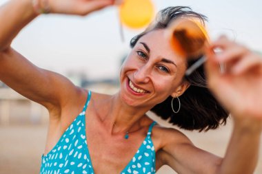 Mutlu kadın gülümsüyor ve sahilde eğleniyor. Genç ve güzel bir kızın yaz portresi. Güneş gözlüklü genç kız. Kız yaz tatilini denizde geçiriyor. Kumsalda dinlenmek..