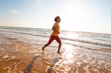 Spor ve sağlık. Bir adam kumsalda koşuyor. Güneşli bir yaz gününde fitness antrenmanı. çalışıyor.