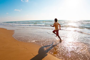 Spor ve sağlık. Bir adam kumsalda koşuyor. Güneşli bir yaz gününde fitness antrenmanı. çalışıyor.
