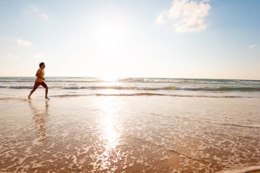 Spor ve sağlık. Bir adam kumsalda koşuyor. Güneşli bir yaz gününde fitness antrenmanı. çalışıyor.
