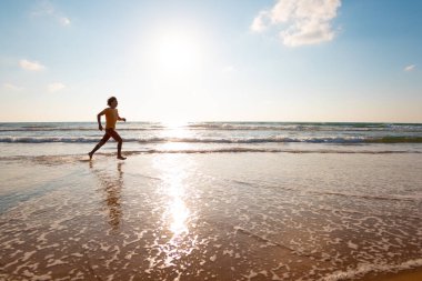 Adam kumsalda koşuyor. Güneşli bir yaz gününde fitness antrenmanı. Sahilde koşmak. spor ve sağlık.