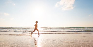 Spor ve sağlık. Bir adam kumsalda koşuyor. Güneşli bir yaz gününde fitness antrenmanı. çalışıyor.