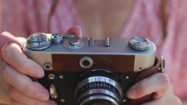 Kameralı kız. Fotoğrafçı kamerayı ayarlar. Elinde analog film kamerası olan modaya uygun bir kadın. seyahat ve tatil.