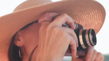 Kameralı fotoğrafçı dışarıda fotoğraf çekiyor. Güzel genç bayan dışarıda eğleniyor. Moda kıyafetleri içinde kameralı güzel, gülümseyen hippi kadın.