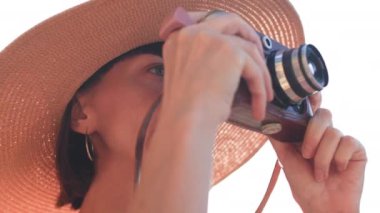 Kameralı fotoğrafçı dışarıda fotoğraf çekiyor. Şapkalı genç kız. Yaz havası. Fotoğrafçı objektifi gösterir ve çekim işleminden zevk alır. seyahat ve tatil.