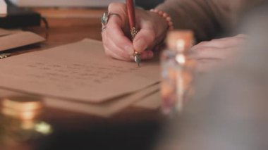 Kalemle yazı yazan bir kızın elini kapat. Mektup yazan profesyonel bir kaligraf. El yazısı sanatı. Yavaş çekim.
