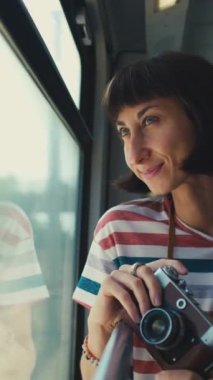 Dikey çekim. Genç bir kadın tren yolculuğundan ve kamerasıyla güzel turistik yerlerin fotoğraflarını çekmekten hoşlanıyor. Tren yolculuğu. Film kamerası. Kız film kamerası kullanıyor..