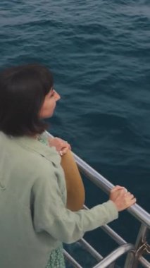 Dikey çekim. Genç bayan bir yolcu gemisinin güvertesinde duruyor ve yolculuğun tadını çıkarıyor. Mutlu kadın. Yatta, tatilde ve seyahatte olan bir kadın. seyahat ve macera.