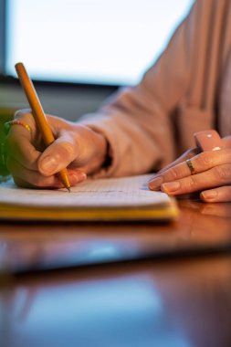 Ofisteki bir kız not defterine not alıyor. Kız dizüstü bilgisayara bakar ve not defterindeki siparişlerin listesini yapar. iş kavramı.