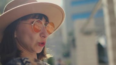 Turuncu güneş gözlüklü genç kız bir arkadaşıyla konuşuyor. Kız güneşli bir günde rahatlar ve iletişim kurar..