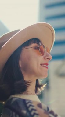 Açık havada şık turuncu gözlük takan güzel beyaz bir kadının moda portresi. Şık giyinmiş bir kızın portresi. Kentsel tarzda bir kız. Yaşam tarzı, bulanık arkaplanda şehir görünümü.