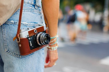 Şık giyinmiş genç bir kız şehirde dolaşıyor ve bir film kamerasıyla fotoğraf çekiyor. Bir film kamerasının yakın çekimi.